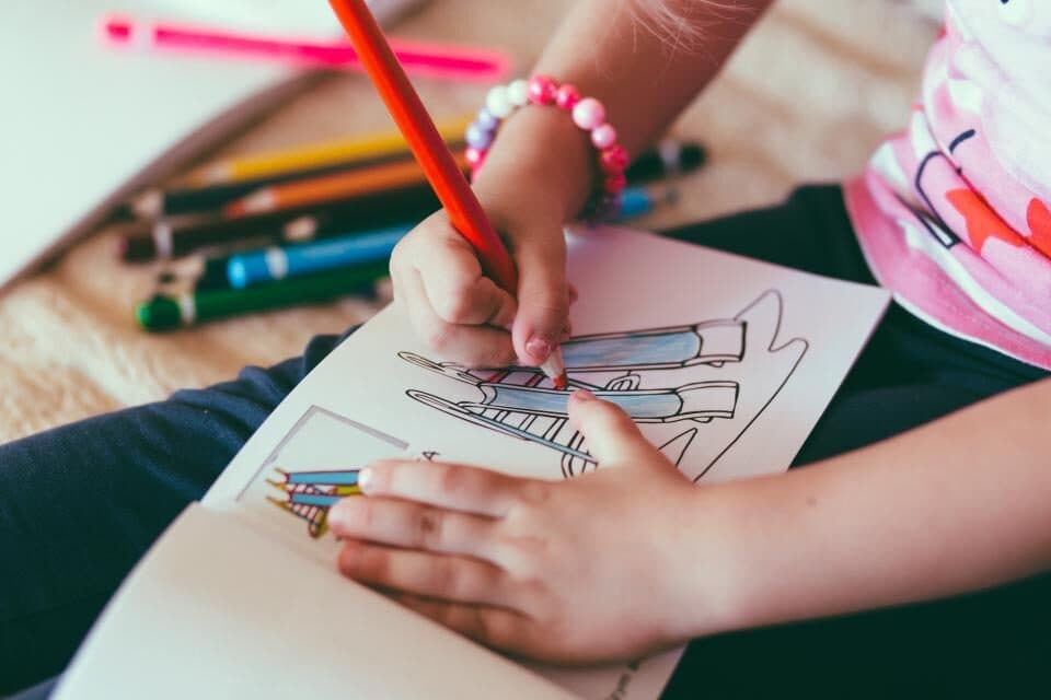 Uma criança a pintar com lápis de cor